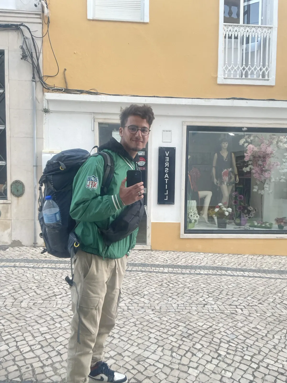 Taha with a backpack on a cobblestone street in Portugal